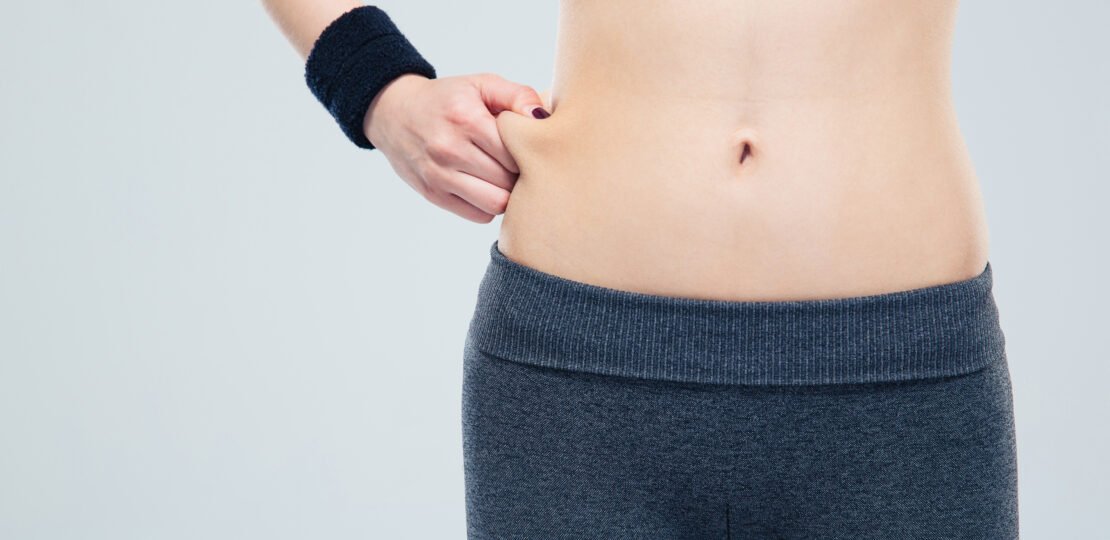 Sporty woman pinch a fat on her abdomen