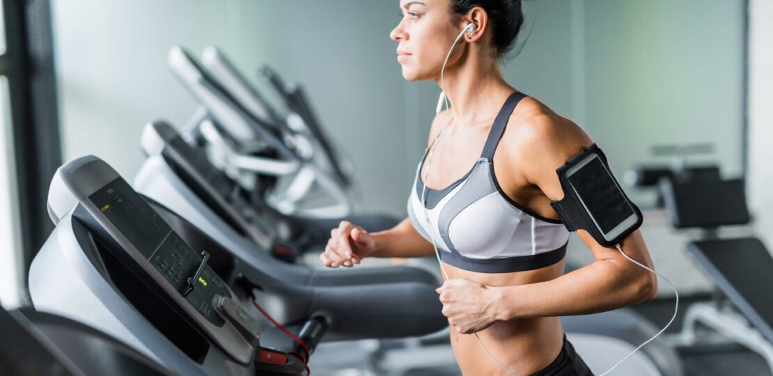 Fit Brunette Woman Running on Treadmill with Music